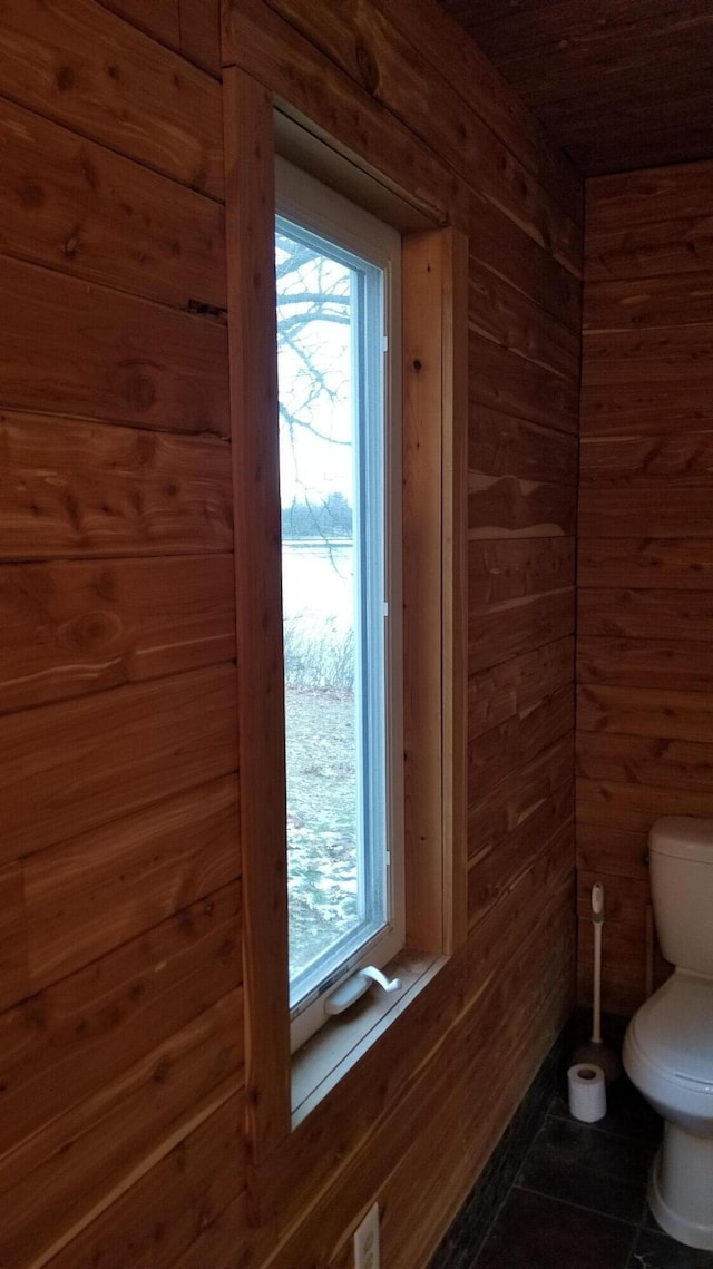 bathroom featuring tile patterned flooring, wooden walls, and toilet