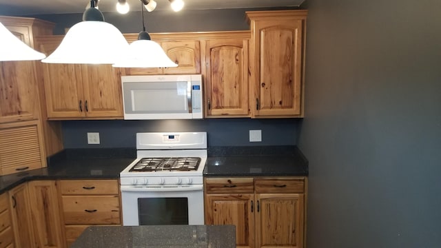 kitchen featuring white range with gas cooktop, decorative light fixtures, and dark stone countertops