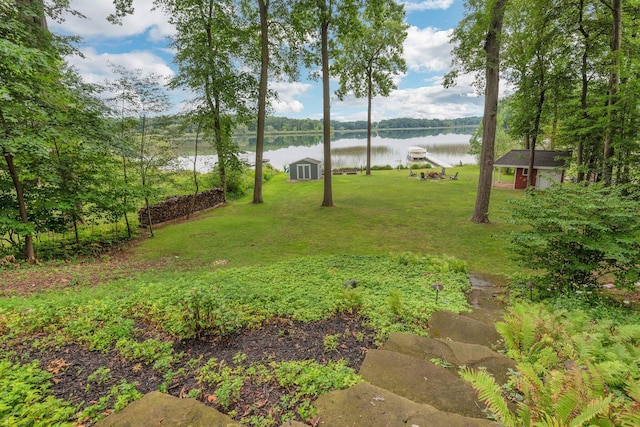 view of yard with a storage shed, an outbuilding, and a water view