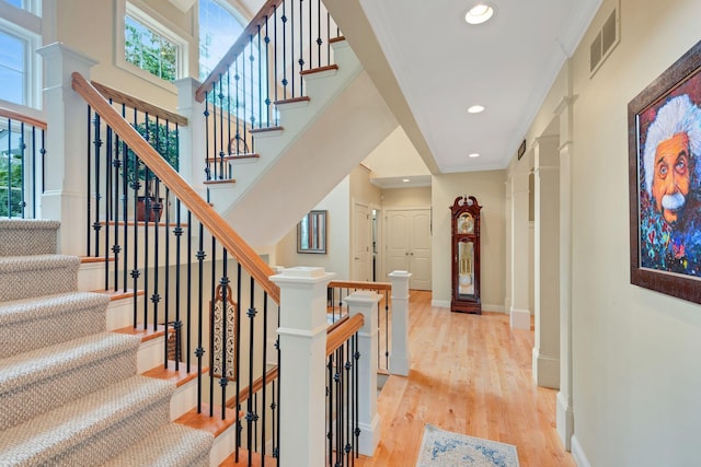 stairway with a wealth of natural light, visible vents, baseboards, and wood finished floors