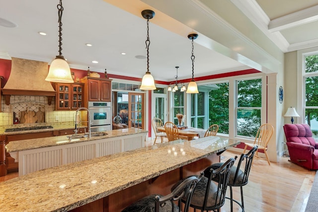 kitchen featuring glass insert cabinets, premium range hood, a breakfast bar area, ornamental molding, and stainless steel appliances