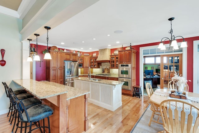 kitchen with a peninsula, custom range hood, light wood-type flooring, and appliances with stainless steel finishes