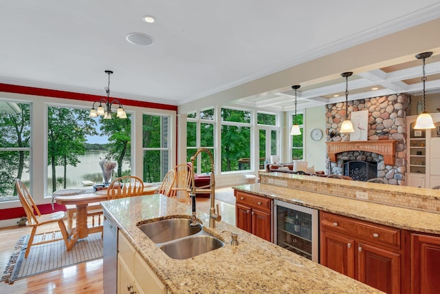 kitchen featuring beverage cooler, brown cabinets, coffered ceiling, and a sink