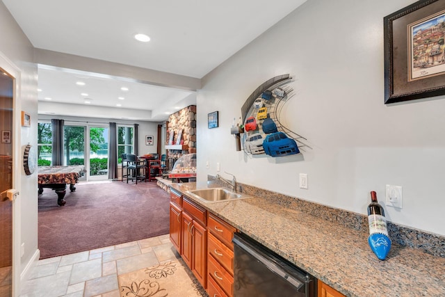 kitchen featuring stone tile floors, light stone counters, a sink, dishwasher, and brown cabinets