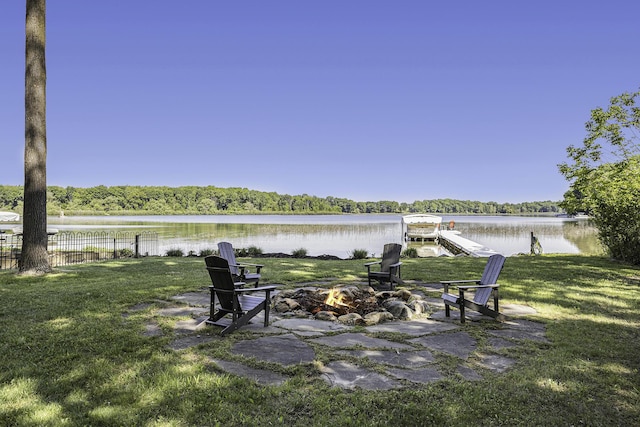 view of yard featuring fence, an outdoor fire pit, a dock, a water view, and a view of trees