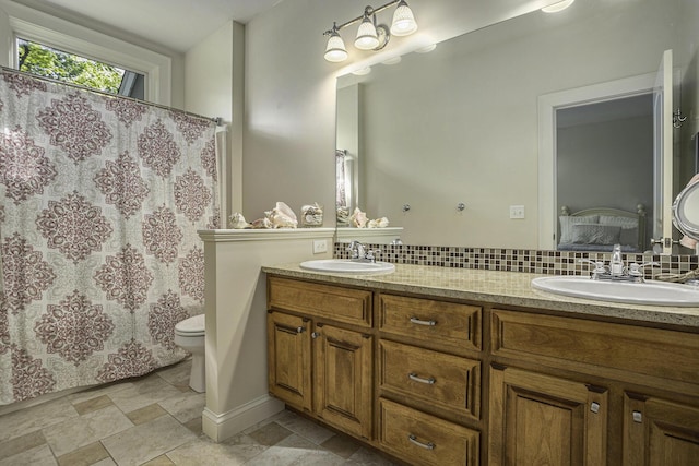 ensuite bathroom featuring toilet, backsplash, ensuite bathroom, and a sink