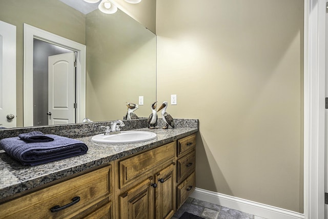 bathroom with baseboards, vanity, and stone finish floor