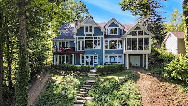 back of house with driveway, a chimney, and a sunroom