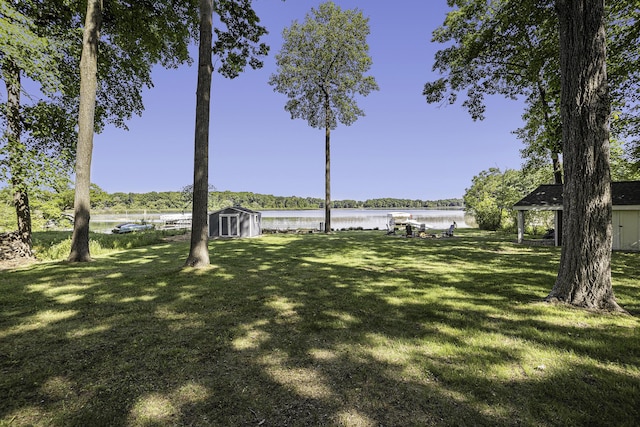 view of yard with a storage unit, a water view, and an outdoor structure