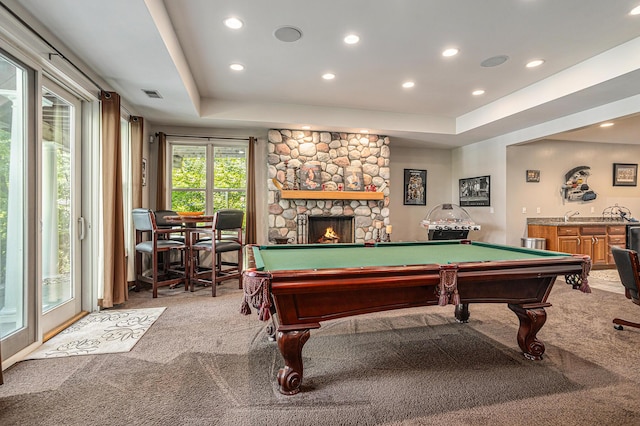 game room with pool table, a tray ceiling, light colored carpet, and a fireplace