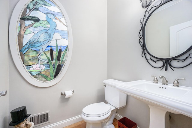 bathroom featuring wood finished floors, baseboards, visible vents, a sink, and toilet