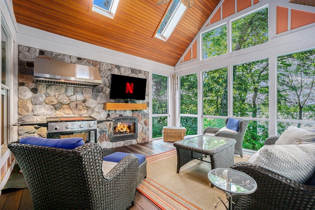 sunroom / solarium featuring a stone fireplace, wooden ceiling, and lofted ceiling with skylight