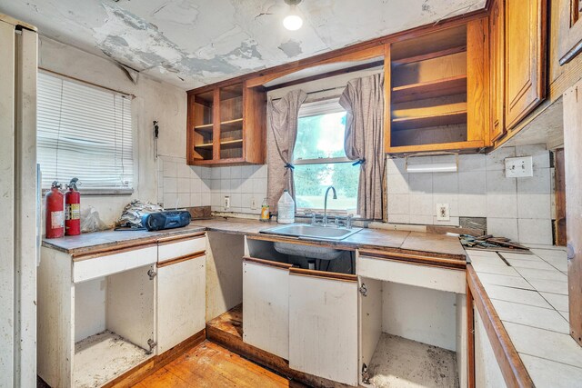 kitchen featuring light hardwood / wood-style floors, sink, decorative backsplash, and tile counters