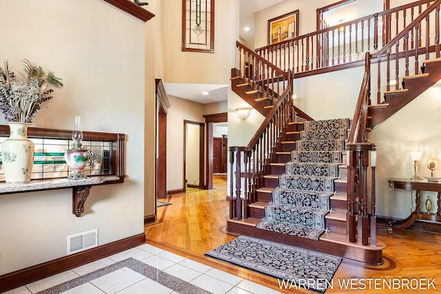 staircase with tile patterned floors and a high ceiling