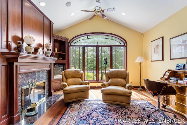 living area featuring hardwood / wood-style flooring, lofted ceiling, plenty of natural light, and a fireplace