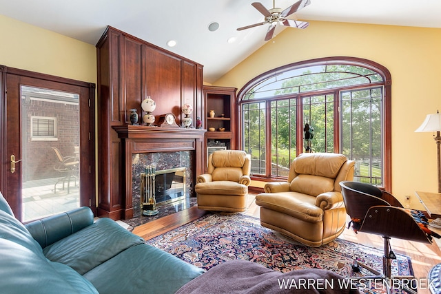 living room with ceiling fan, lofted ceiling, a high end fireplace, and hardwood / wood-style floors