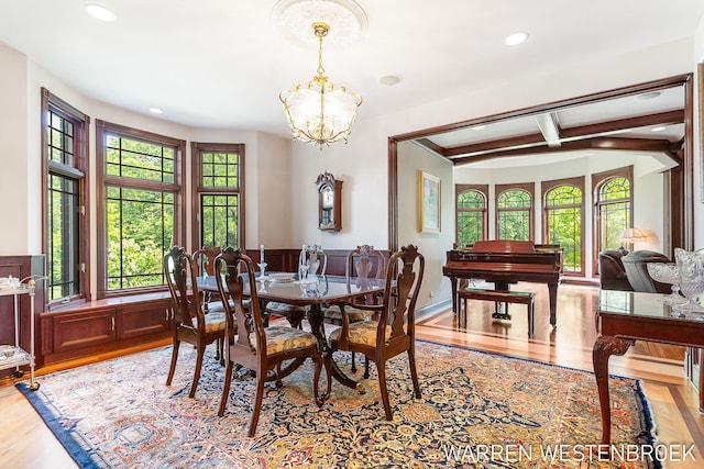 dining area featuring an inviting chandelier, beam ceiling, and light hardwood / wood-style floors