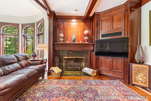 living room featuring light hardwood / wood-style floors, a premium fireplace, and beamed ceiling