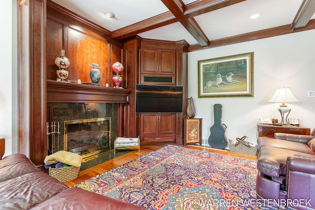 living room with coffered ceiling, beamed ceiling, crown molding, a tile fireplace, and hardwood / wood-style flooring