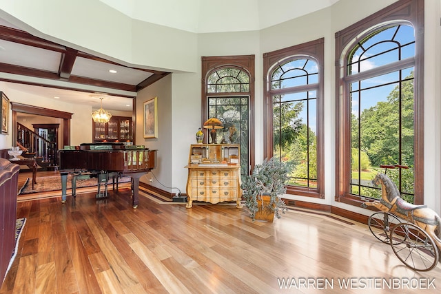 interior space with plenty of natural light, beam ceiling, hardwood / wood-style floors, and a notable chandelier