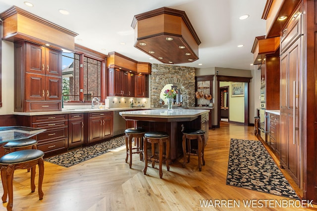 kitchen with a breakfast bar, sink, light wood-type flooring, a kitchen island, and oven