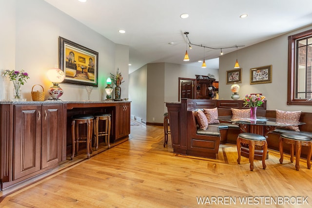 living room with indoor bar and light hardwood / wood-style flooring