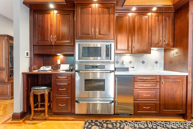 kitchen with appliances with stainless steel finishes, backsplash, and light hardwood / wood-style floors