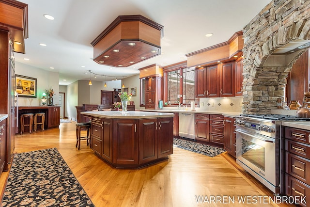 kitchen featuring a kitchen bar, a kitchen island, stainless steel appliances, light hardwood / wood-style floors, and decorative backsplash