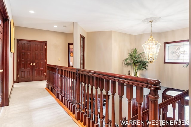 hallway with light colored carpet and an inviting chandelier