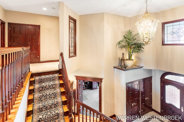 staircase with an inviting chandelier