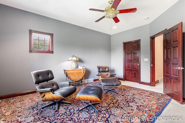 living area featuring light colored carpet and ceiling fan