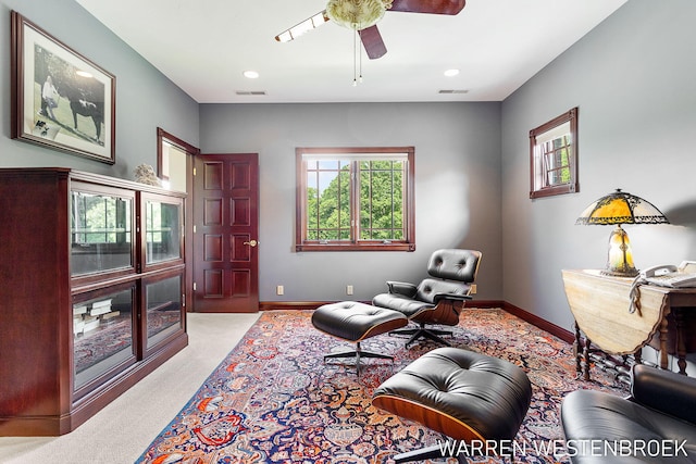 living area with light carpet and ceiling fan