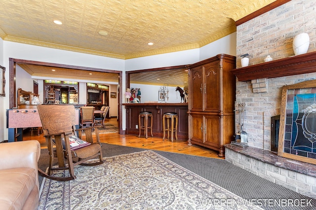 living room with hardwood / wood-style flooring, ornamental molding, indoor bar, and a fireplace