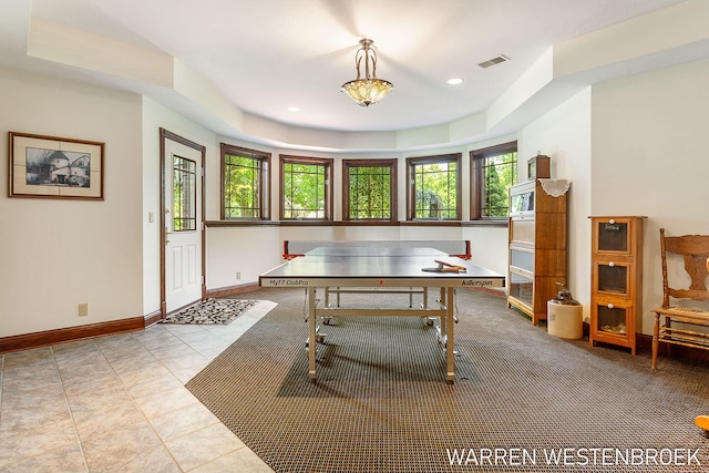 game room with a raised ceiling and light tile patterned floors