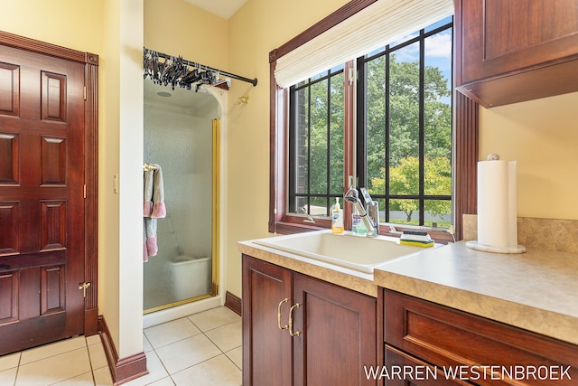 bathroom with an enclosed shower, vanity, tile patterned floors, and decorative columns