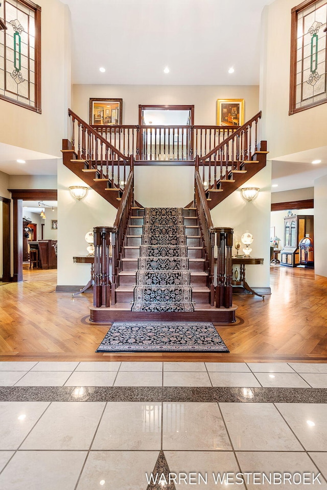 staircase with wood-type flooring and a towering ceiling