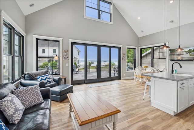 living room with sink, a wealth of natural light, high vaulted ceiling, and light hardwood / wood-style floors