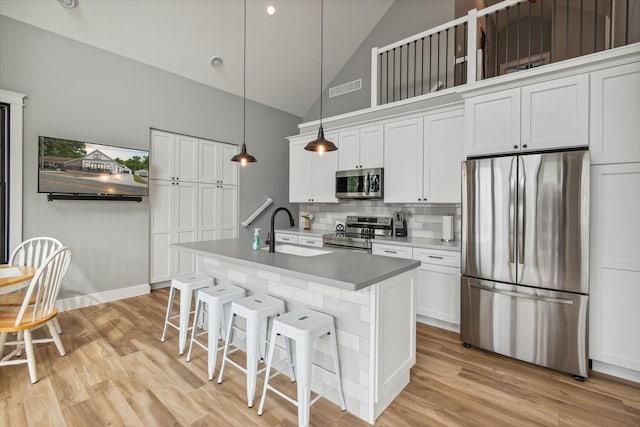 kitchen featuring stainless steel appliances, a kitchen island with sink, sink, and white cabinets