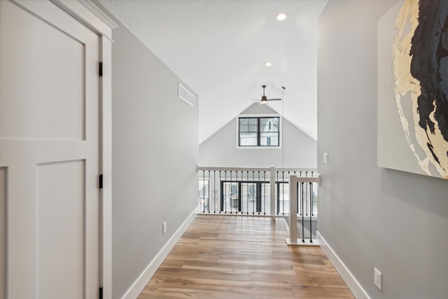 hallway featuring vaulted ceiling and light hardwood / wood-style flooring