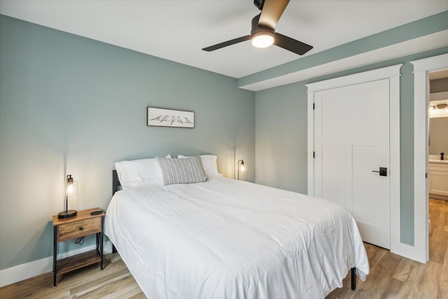 bedroom with ceiling fan, ensuite bath, and light hardwood / wood-style flooring