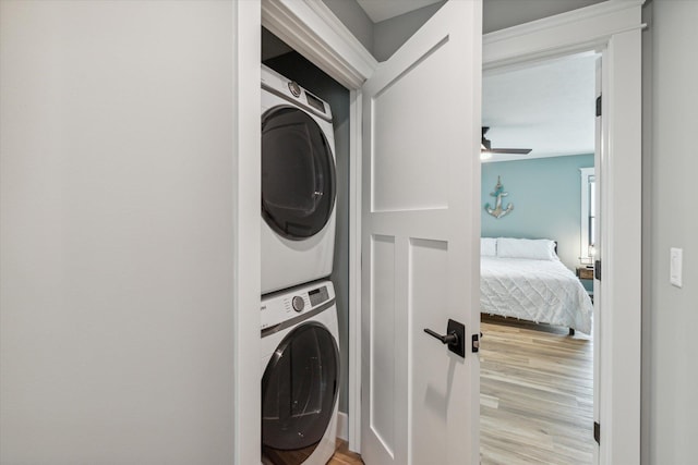 washroom with stacked washer / drying machine, ceiling fan, and light wood-type flooring