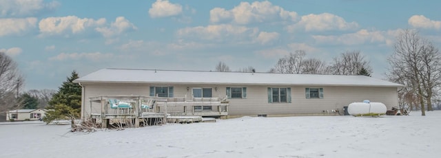 snow covered back of property featuring a deck