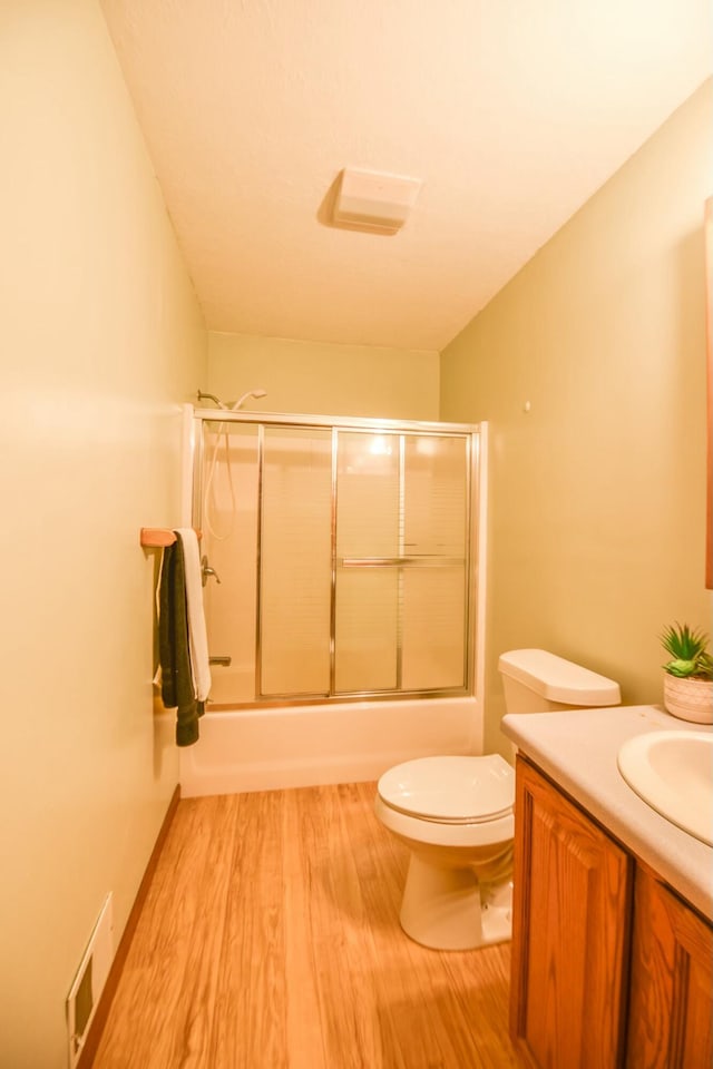 full bathroom featuring hardwood / wood-style floors, vanity, toilet, and enclosed tub / shower combo