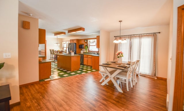 dining room with sink, wood-type flooring, and an inviting chandelier