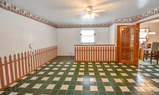 empty room with ceiling fan with notable chandelier and a textured ceiling