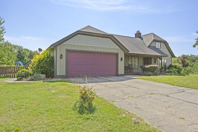 view of front of house featuring a garage, covered porch, and a front lawn