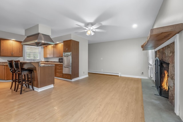 kitchen featuring extractor fan, a fireplace, a baseboard heating unit, a kitchen breakfast bar, and ceiling fan