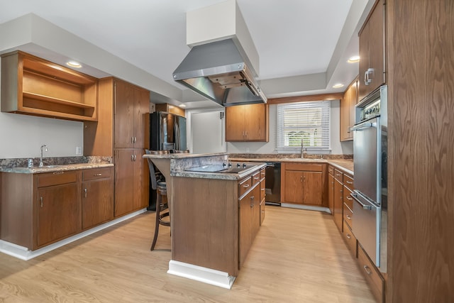 kitchen with black appliances, sink, a kitchen bar, light hardwood / wood-style flooring, and island range hood