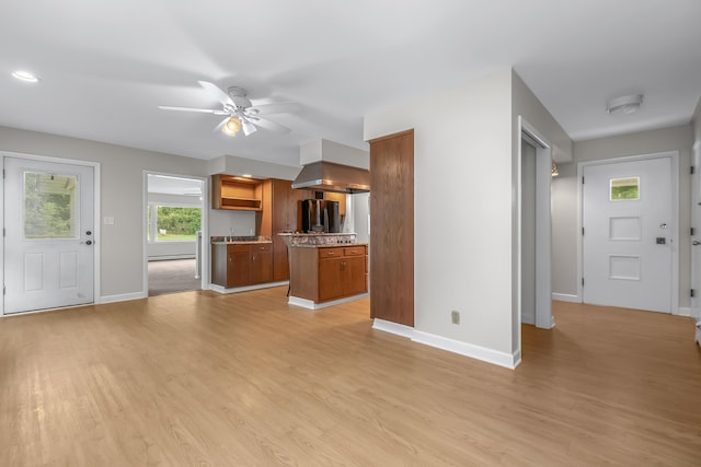 unfurnished living room with a baseboard heating unit, light wood-type flooring, and ceiling fan