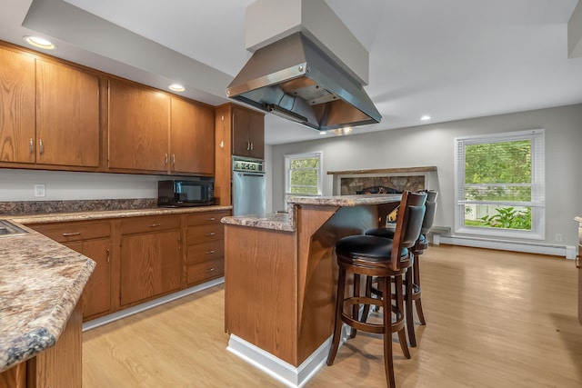 kitchen with oven, light hardwood / wood-style flooring, a healthy amount of sunlight, and island exhaust hood